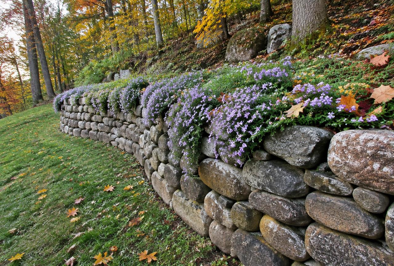 Tiered natural stone retaining wall with perennial plantings on a sloped yard
